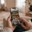 Eine Person schaut auf ihrem Smartphone Bilder von Hotelzimmern und Landschaften, während sie in einem modernen Wohnraum sitzt.