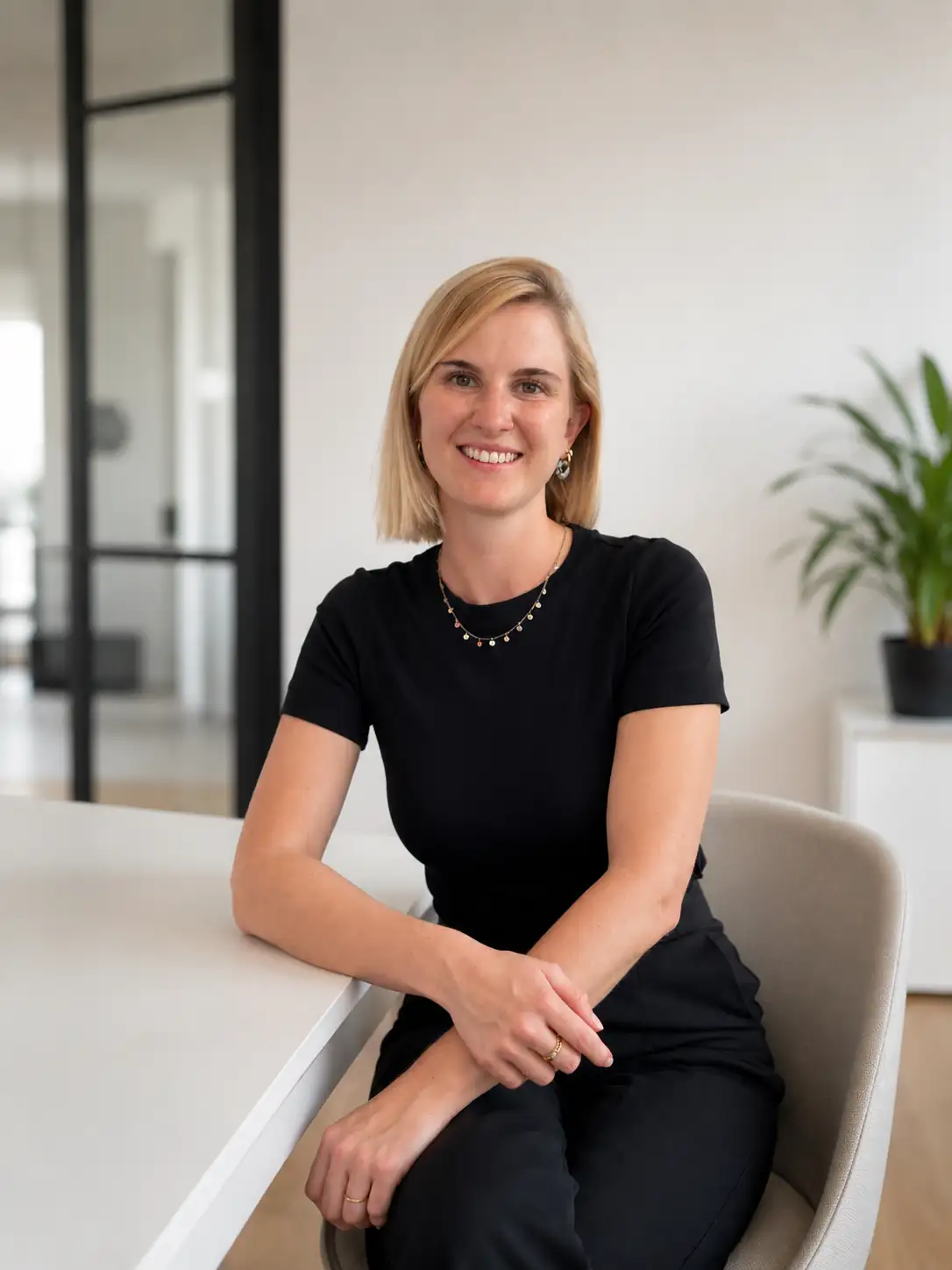 Professionelles Portrait einer lächelnden Frau in einem modernen Büro Eine Frau im schwarzen T-Shirt sitzt in einem modernen Büroumfeld und lächelt freundlich. Die moderne Architektur und Dekoration sind zu sehen.